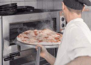 A man is using on of the best commercial pizza ovens to make crispy and perfect pizza